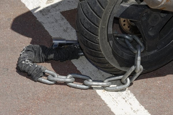 Marseille, A motorbike tyre with a safety chain and a brake disc lock on asphalt, Marseille, Departement Bouches-du-Rhone, Provence-Alpes-Cote d'Azur region, France, Europe