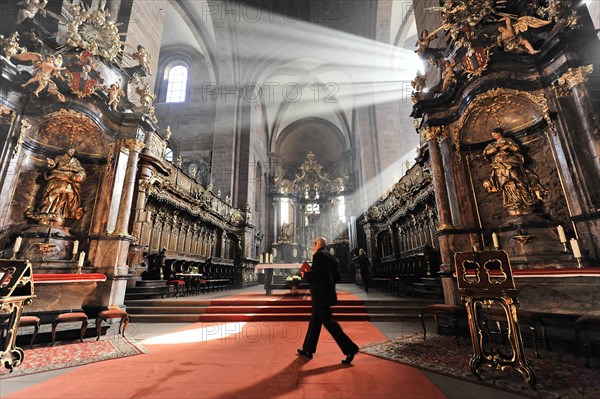 Speyer Cathedral, A person walks through the church aisle while rays of light illuminate the baroque altars, Speyer Cathedral, Unesco World Heritage Site, foundation stone laid around 1030, Speyer, Rhineland-Palatinate, Germany, Europe