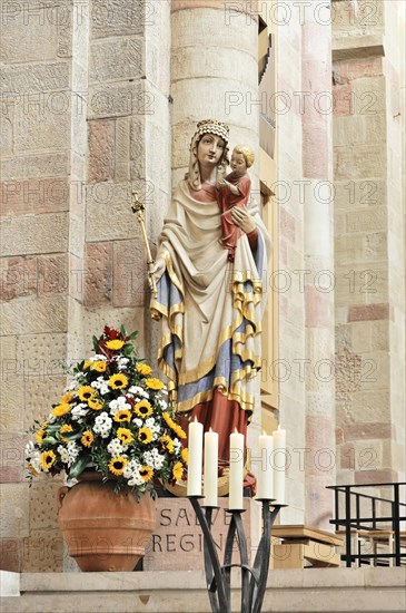 Speyer Cathedral, Colourful sculpture of a saint with child, surrounded by flowers and candles, Speyer Cathedral, Unesco World Heritage Site, foundation stone laid around 1030, Speyer, Rhineland-Palatinate, Germany, Europe