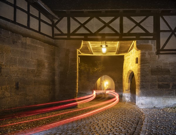 View through the Spitaltor at dusk in fog, traces of light from a car, Rothenburg ob der Tauber, Middle Franconia, Bavaria, Germany, Europe