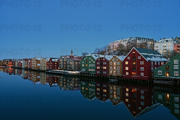 Historic warehouse buildings reflected in the river Nidelva at dusk, Bryggene, Trondheim, Norway, Europe