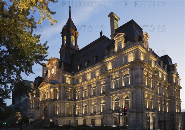 Second empire style multistory Montreal City Hall building facade with lights on at dusk, Old Montreal, Quebec, Canada, North America