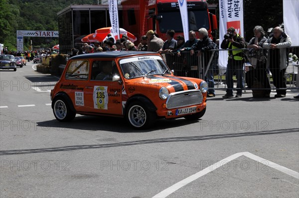 An orange and black Mini Cooper starts on a rally surrounded by spectators, SOLITUDE REVIVAL 2011, Stuttgart, Baden-Wuerttemberg, Germany, Europe