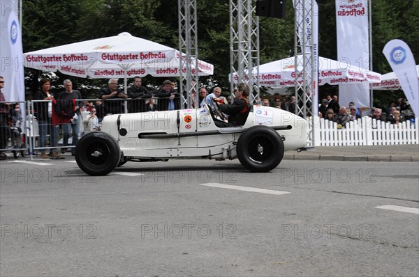 A vintage racing car drives past a crowd of people and advertising banners, SOLITUDE REVIVAL 2011, Stuttgart, Baden-Wuerttemberg, Germany, Europe