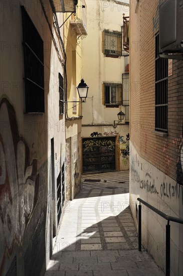 Jaen, Sunny day falls in a narrow, shaded alley with old buildings and a alleyway lamp, Jaen, Andalusia, Spain, Europe