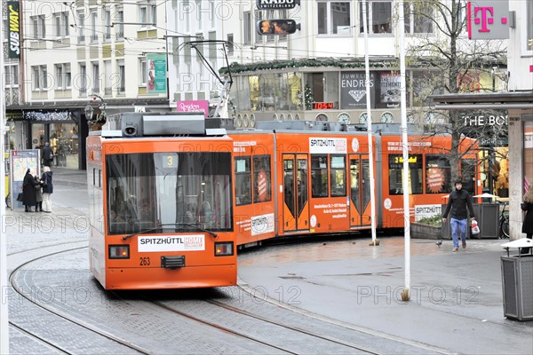 Wuerzburg, Orange tram travelling through an urban street with tracks and passers-by, Wuerzburg, Lower Franconia, Bavaria, Germany, Europe