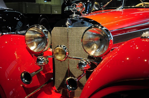Front view of a red classic car with shiny headlights and chrome accents, Mercedes-Benz Museum, Stuttgart, Baden-Wuerttemberg, Germany, Europe
