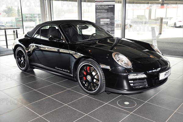 A black Porsche 911 Coupe on display in a showroom, Schwaebisch Gmuend, Baden-Wuerttemberg, Germany, Europe