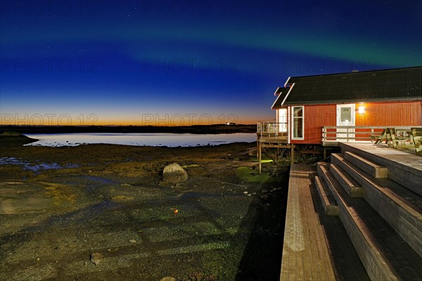 Red building with balcony by the water, Northern lights (aurora borealis), Rorbuer, holiday, accommodation, Lovund, Lovunden, Helgeland coast, Norway, Europe