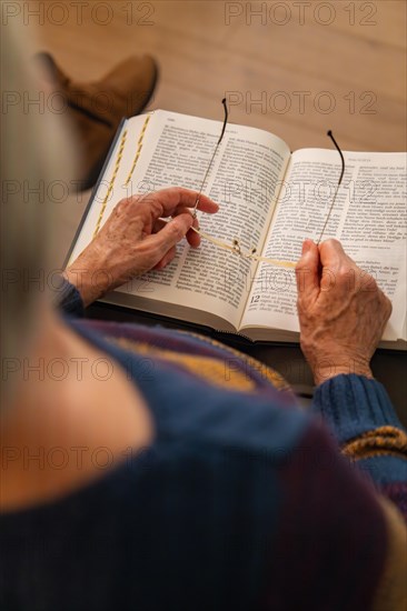 An elderly person sitting and reading a book, holding the glasses in his hands, Bible Circle, Jesus Grace Chruch, Ludwigsburg, Germany, Europe