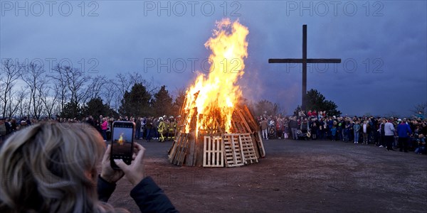 A woman photographs the Easter bonfire on the Haniel spoil tip in front of the summit cross, Bottrop, Ruhr area, North Rhine-Westphalia, Germany, Europe