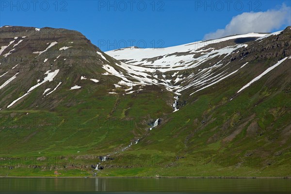 Waterfall and desolate farm along the fjord Seyoisfjoerour, Seydisfjoerdur in summer, Eastern Region, Austurland, Iceland, Europe