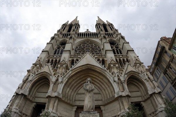 Church of Saint-Vincent-de-Paul, exterior view of a Gothic-style church with a statue in the foreground under a cloudy sky, Marseille, Departement Bouches-du-Rhone, Provence-Alpes-Cote d'Azur region, France, Europe