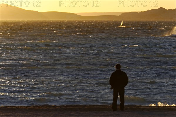 Marseille in the evening, A person stands on the shore and looks at the sea during sunset, Marseille, Departement Bouches-du-Rhone, Region Provence-Alpes-Cote d'Azur, France, Europe