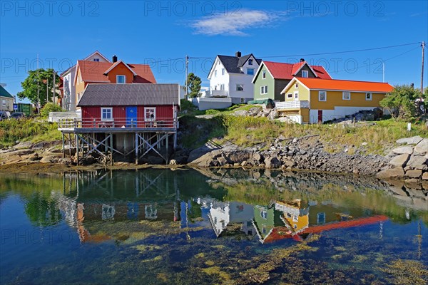 Small, colourful fishermen's houses are reflected in the calm waters of a small harbour, Rorbuer, holiday, Henningsvaer, Nordland, Lofoten, Norway, Europe
