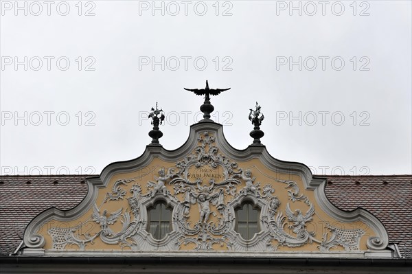 Facade view of the Falkenhaus with stucco facade in rococo style in the centre of Wuerzburg, Baroque facade with elaborate stucco work and an eagle on the roof peak under a grey sky, Wuerzburg, Lower Franconia, Bavaria, Germany, Europe