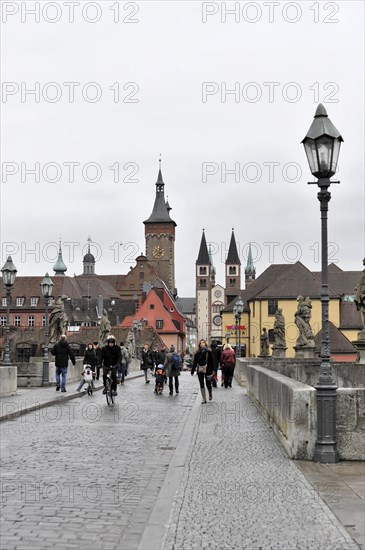 Wuerzburg, Busy pedestrians on a bridge with historic buildings and a tower in the background, Wuerzburg, Lower Franconia, Bavaria, Germany, Europe