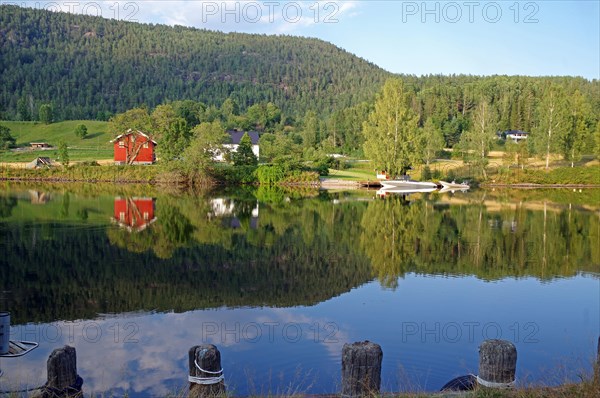 Trees, houses and a small boat are reflected in a calm lake, old waterway, Telemark Canal, Telemark, Norway, Europe