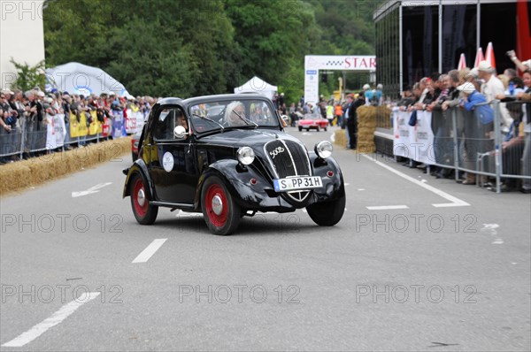 A small black vintage car is cheered by spectators during a street race, SOLITUDE REVIVAL 2011, Stuttgart, Baden-Wuerttemberg, Germany, Europe
