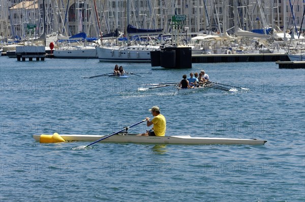 Marseille harbour, people rowing on the sea, an athlete in the foreground, Marseille, Departement Bouches-du-Rhone, Provence-Alpes-Cote d'Azur region, France, Europe