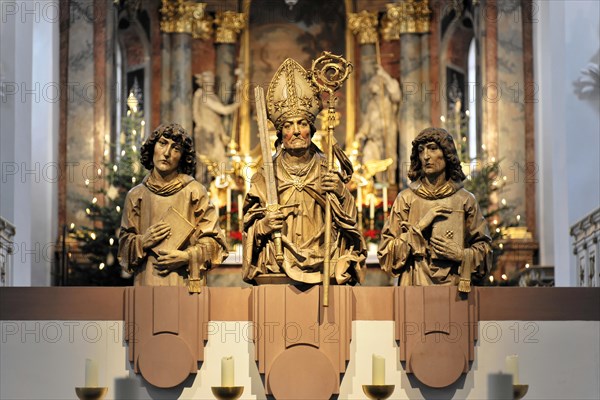 Wuerzburg, Three sculptured figures of saints on an altar with candles and a Christmas tree in the background, Wuerzburg, Lower Franconia, Bavaria, Germany, Europe
