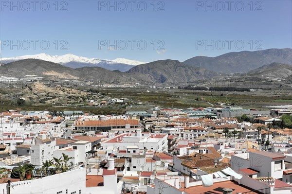 Solabrena, panoramic view over a town with white houses in front of the snow-covered Sierra Nevada, Andalusia, Spain, Europe