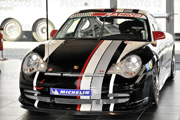 A black Porsche racing car with white and red stripes stands in the showroom, Schwaebisch Gmuend, Baden-Wuerttemberg, Germany, Europe