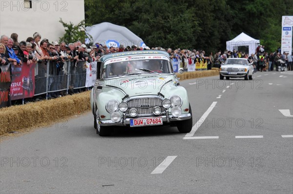 A white vintage racing car drives past spectators and hay bales on a road rally, SOLITUDE REVIVAL 2011, Stuttgart, Baden-Wuerttemberg, Germany, Europe