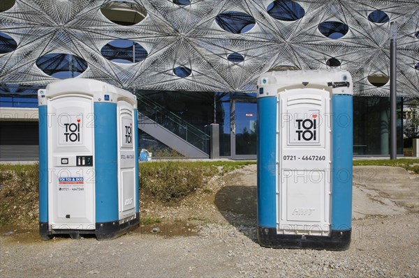 Construction site toilet, sanitary facility, toilet, mobile toilet, TOI TOI, Dixi, DIXI, zero zero, Reutlingen University site, Reutlingen University, Texoversum at the back, German University Building Award 2024 for TEXOVERSUM, modern architecture, facade made of carbon and glass fibres, mesh, innovative, identity-creating, unique facade, campus, place of learning, special, extraordinary new building for textile courses, Reutlingen, Baden-Wuerttemberg, Germany, Europe