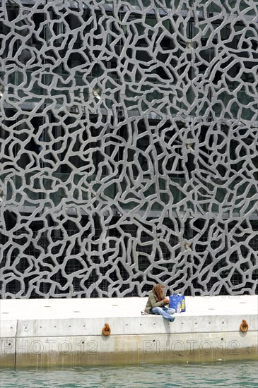 Marseille, A person sits on the quay wall, reads a book and enjoys the peace and quiet by the water, Marseille, Departement Bouches-du-Rhone, Region Provence-Alpes-Cote d'Azur, France, Europe