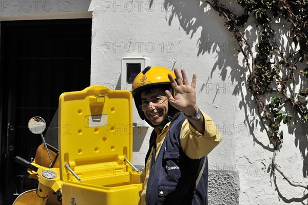 Solabrena, A smiling postman in a yellow uniform greets friendly while delivering the mail, Andalusia, Spain, Europe