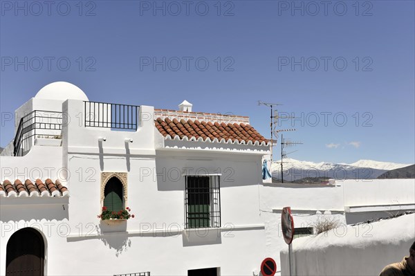 Solabrena, Traditional white building with tiled roof and round arch in front of the Sierra Nevada, Andalusia, Spain, Europe