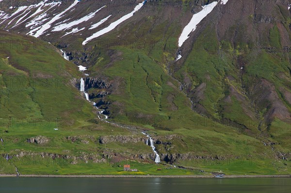 Waterfall and desolate farm along the fjord Seyoisfjoerour, Seydisfjoerdur in summer, Eastern Region, Austurland, Iceland, Europe