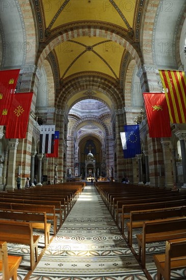 Marseille Cathedral or Cathedrale Sainte-Marie-Majeure de Marseille, 1852-1896, Marseille, View through the nave of a church with pews and various flags on the pillars, Marseille, Departement Bouches-du-Rhone, Region Provence-Alpes-Cote d'Azur, France, Europe