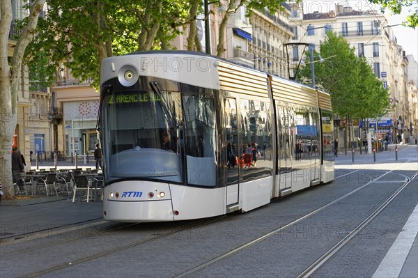 Tram travelling through an urban scene with trees and buildings, Marseille, Departement Bouches-du-Rhone, Provence-Alpes-Cote d'Azur region, France, Europe