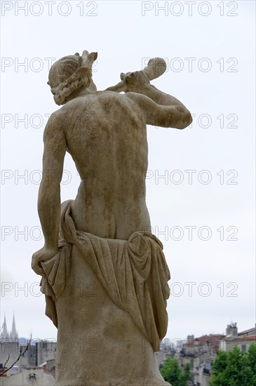 Palais Longchamp, Marseille, Back view of a classical stone figure in front of a blurred city background, Marseille, Departement Bouches-du-Rhone, Region Provence-Alpes-Cote d'Azur, France, Europe
