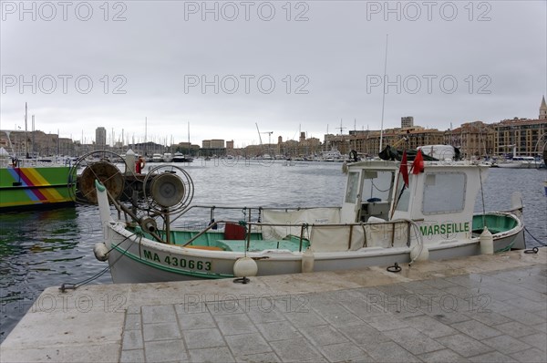 Marseille, Boat at the quay in the harbour of Marseille with calm water surface and city view in the background, Marseille, Departement Bouches-du-Rhone, Region Provence-Alpes-Cote d'Azur, France, Europe