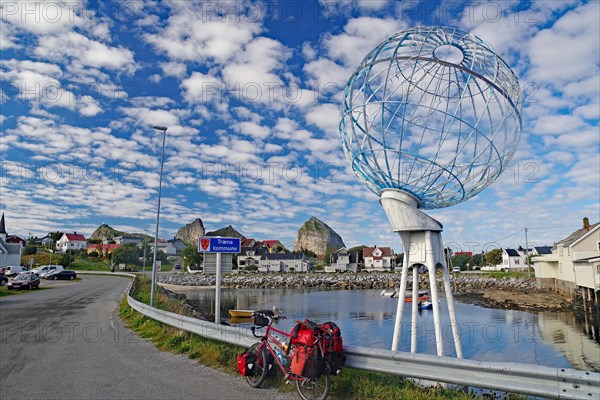 Packed touring bike in front of a huge globe and a harbour, Traena, Lovunden, Helgeland coast, Norway, Europe