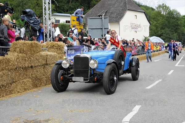 An old racing car is accompanied by a person with a flag, spectators watch the event, SOLITUDE REVIVAL 2011, Stuttgart, Baden-Wuerttemberg, Germany, Europe