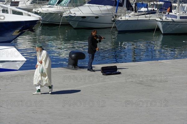 A street musician performs for an audience on a sunny harbour promenade, Marseille, Departement Bouches-du-Rhone, Provence-Alpes-Cote d'Azur region, France, Europe