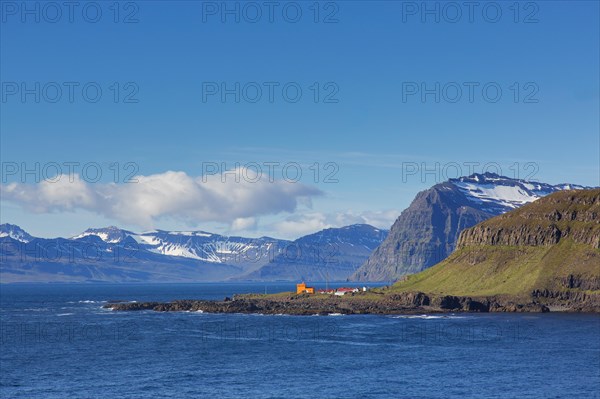 Rugged mountains and orange lighthouse at Skalanes along the fjord Seyoisfjoerour, Seydisfjoerdur in summer, Eastern Region, Austurland, Iceland, Europe