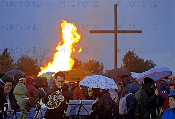 Musicians with a double horn in front of the Easter bonfire on the Haniel spoil tip with the summit cross in the rain, Bottrop, Ruhr area, Germany, Europe