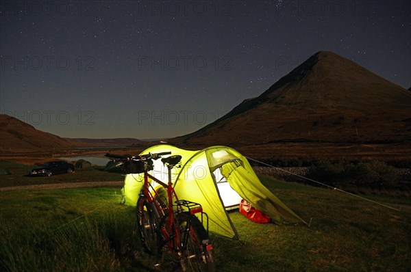 Tent illuminated with a torch in front of rugged mountains, bicycle, Cullins, Isle of Skye, Hebrides, Scotland, Great Britain