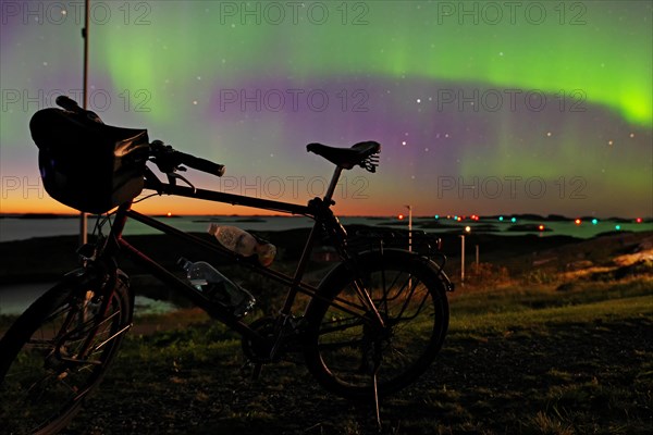 Northern lights (aurora borealis) mingle with sunset, bike without luggage, Lovunden, Helgeland coast, Traena, Norway, Europe