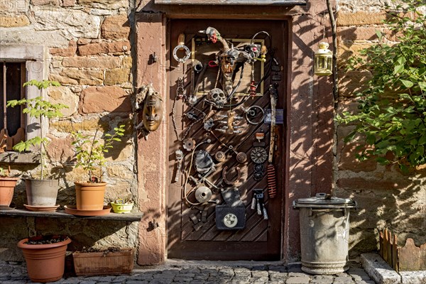 Old half-timbered house, whimsically decorated, flower pots, door with masks, skulls, engine parts, cartridge cases, tools, old town, Ortenberg, Vogelsberg, Wetterau, Hesse, Germany, Europe