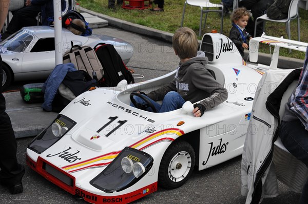 A child plays in a white Porsche replica at a motorsport event, SOLITUDE REVIVAL 2011, Stuttgart, Baden-Wuerttemberg, Germany, Europe
