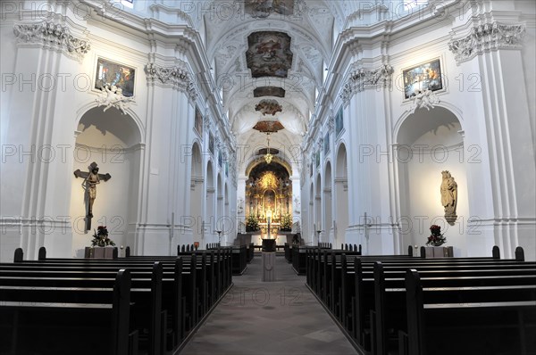 The Neumuenster Collegiate Abbey, Diocese of Wuerzburg, A bright baroque church interior with rows of pews and a centred cross at the front, Wuerzburg, Lower Franconia, Bavaria, Germany, Europe