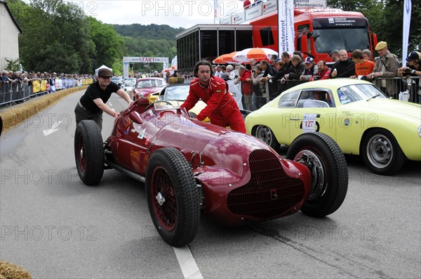 A red vintage racing car is pushed by a man in a race while spectators watch, SOLITUDE REVIVAL 2011, Stuttgart, Baden-Wuerttemberg, Germany, Europe
