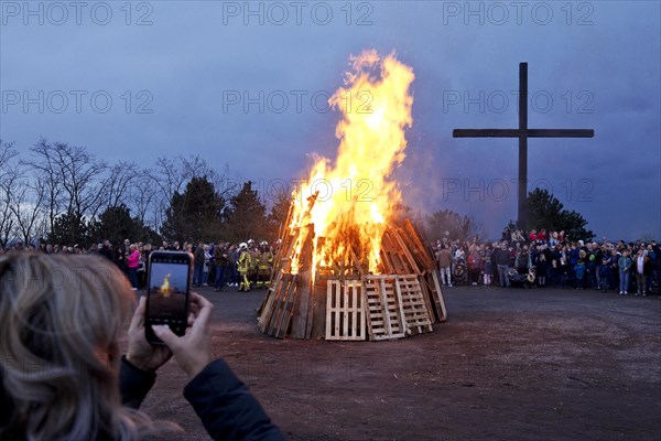 A woman photographs the Easter bonfire on the Haniel spoil tip in front of the summit cross, Bottrop, Ruhr area, North Rhine-Westphalia, Germany, Europe