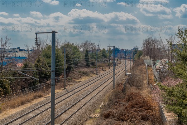 Train tracks running through industrial area on outskirts of small town under cloudy sky in South Korea